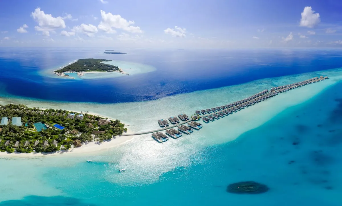 Aerial view of a Maldives resort island with overwater villas and white sandbank