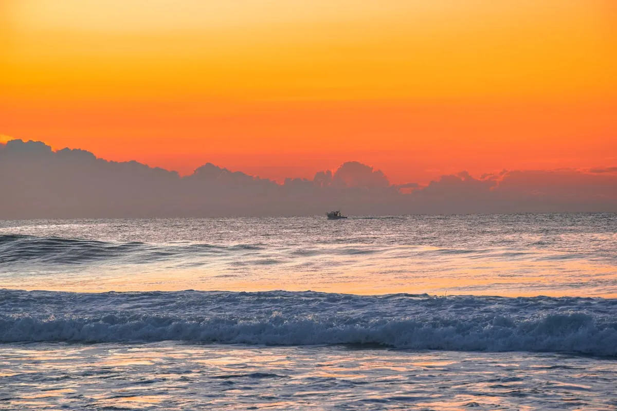 A boat sailing on the ocean at sunset